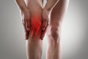 Person grabbing knee in pain from Knee Osteoarthritis