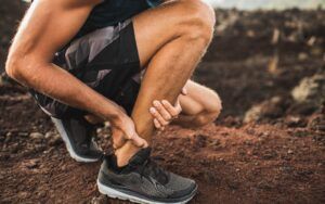 Athletic Man Expericing Ankle Problems Outdoors